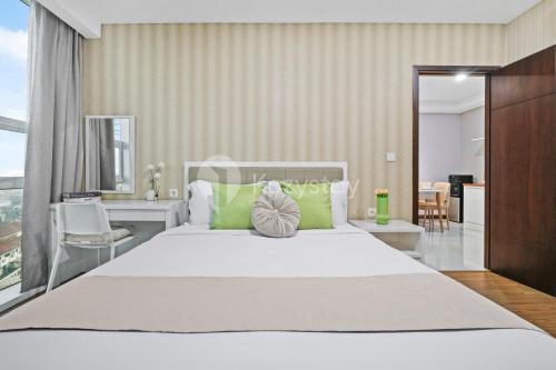 a bedroom with a large white bed with green pillows at Sepia By Kozystay - MACAN Museum - Kebon Jeruk in Jakarta