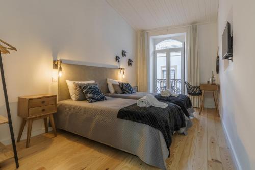 a bedroom with a bed and a table and a window at Casas da Ferraria by 4U Alojamento in Abrantes