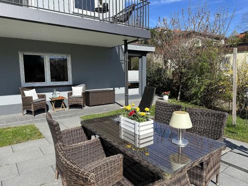 un patio con una mesa con sillas de mimbre y una mesa con flores en Haus Albi en Waldkirch