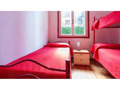 1 dormitorio rojo con 2 camas y ventana en Villa Verde, en Eraclea Mare