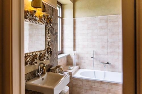 a bathroom with a tub and a sink and a mirror at La Sergiunga del Monferrato in Casorzo