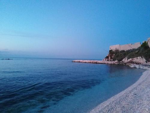 una spiaggia con acqua blu e un edificio sullo sfondo di Amasté in Puglia CASA VACANZA a Bisceglie