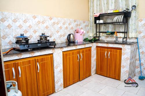 - une cuisine avec des placards en bois et une cuisinière dans l'établissement Kica Apartment with Airconditioned bedrooms in Lira, Uganda, à Lira