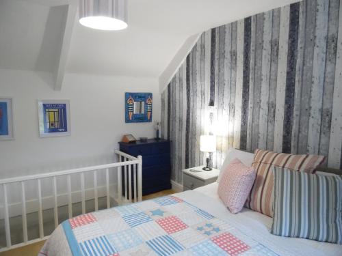 een slaapkamer met een bed met een blauwe en witte deken bij Langdon Farm Cottage in Boyton