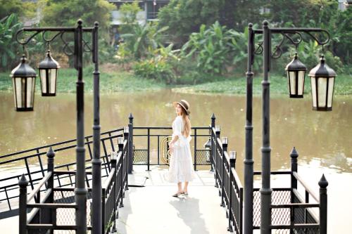 a woman in a white dress standing on a bridge at Buri Sriping Riverside Resort & Spa in Chiang Mai