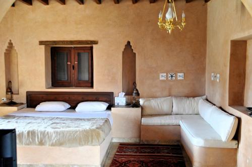 a bedroom with a bed and a couch and a chandelier at El Beyt Farmhotel in Az Zabū