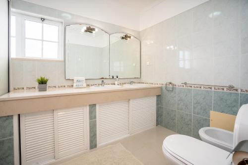 a bathroom with a sink and a mirror and a toilet at Casa da Amoreira in Alvor