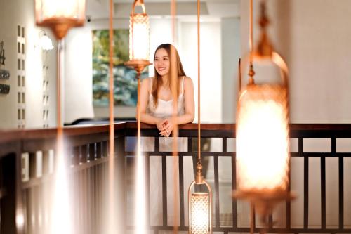 a woman sitting on a railing with several lights at Buri Sriping Riverside Resort & Spa in Chiang Mai