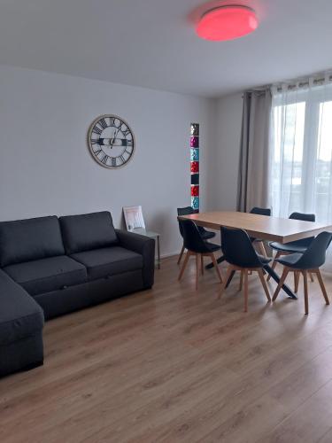 een woonkamer met een tafel, een bank en een klok bij Appartement proche PARIS/STADE DE FRANCE in Épinay-sur-Seine