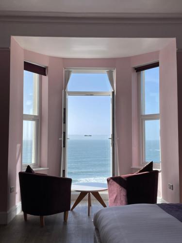 a bedroom with a large window overlooking the ocean at Lundy House Hotel in Woolacombe