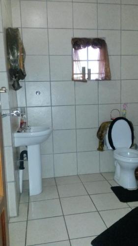 a bathroom with a toilet and a sink and a window at Magnolia Guesthouse & coffeeshop in Vaalpark