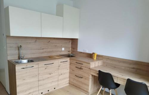 una cocina con armarios blancos, fregadero y 2 sillas en Modern Studio Apartment, en Liubliana