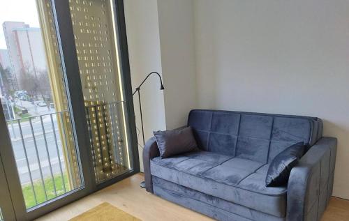 Sofá azul en una habitación con ventana grande en Modern Studio Apartment, en Liubliana