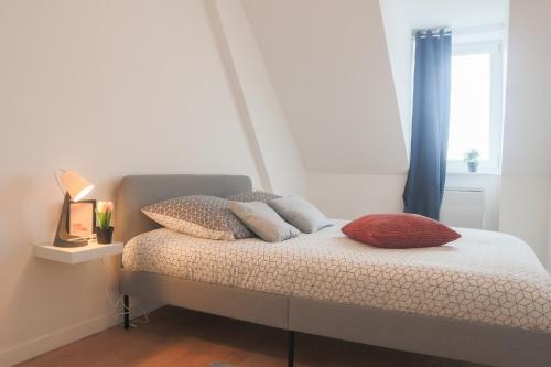 een slaapkamer met een bed met kussens en een raam bij LE SUNNY, Mulhouse centre in Mulhouse