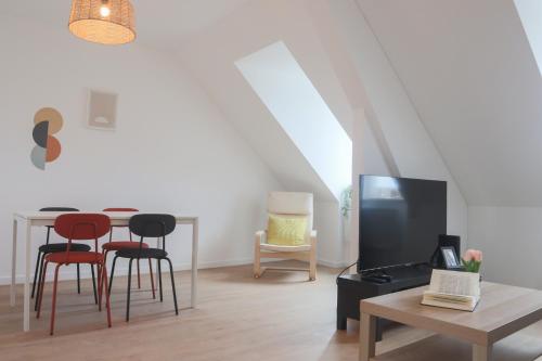 een woonkamer met een tafel en stoelen en een televisie bij LE SUNNY, Mulhouse centre in Mulhouse