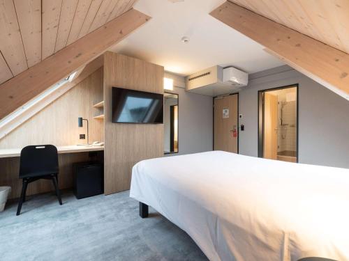 una camera con un grande letto e una TV a parete di ibis Chur a Coira