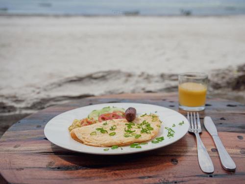 a plate of food on a table with a glass of orange juice at Just Heaven Apartments in Matemwe