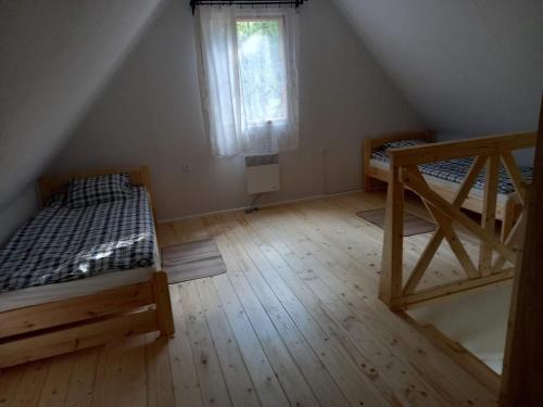 um quarto no sótão com 2 camas e uma janela em Drewniany domek wakacyjny em Człuchów