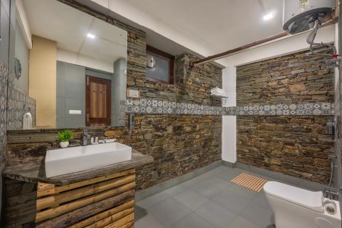 a bathroom with a sink and a stone wall at Hotel Wood Winds - Best Hotel in Chail in Shimla