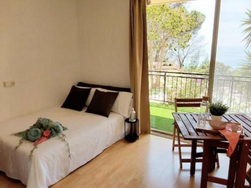 Un dormitorio con una cama y una mesa y un balcón. en Loft con vistas al Mar en Costa Brava, en Santa Cristina d'Aro