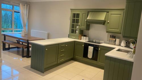 a kitchen with green cabinets and a table in it at Sawgrass Killinard in Killenard