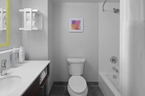 a bathroom with a toilet and a sink and a tub at Hampton Inn & Suites Grand Rapids-Airport 28th St in Cascade