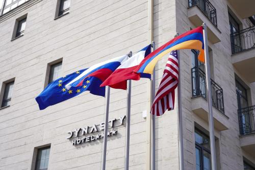tres banderas están volando delante de un edificio en Hotel Dynasty en Ereván
