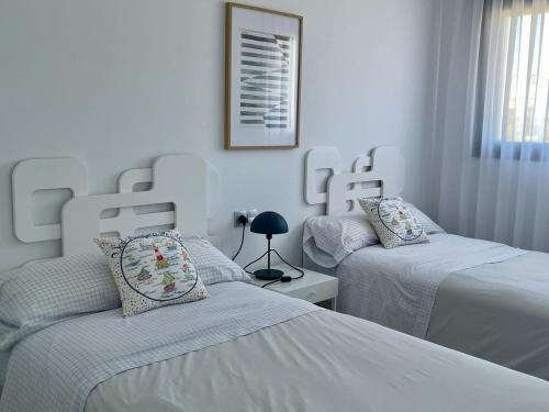 dwa łóżka w sypialni z białymi ścianami w obiekcie Elegante apartamento en Jardines de Montesolana w mieście Los Dolses