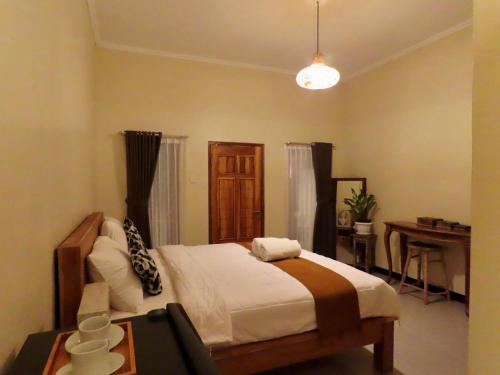 a bedroom with a bed and a desk and a table at Blue Waves Balangan Homestay in Uluwatu
