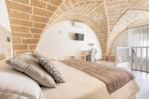 um quarto com uma cama grande numa parede de tijolos em Clara Domus em Gallipoli