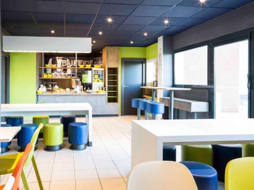 a restaurant with colorful chairs and tables in a cafeteria at Ibis Budget Orly Chevilly Tram 7 in Chevilly-Larue