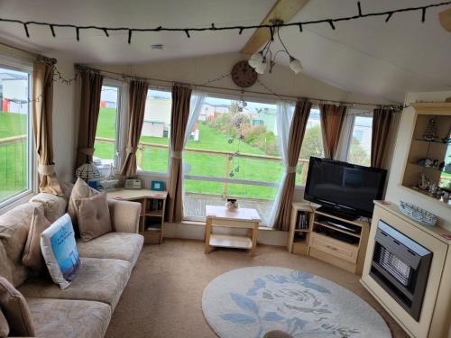 a living room with a couch and a tv at Cosy caravan Sunbeach in Llwyngwril