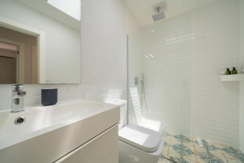 a white bathroom with a toilet and a sink at Lanzahost Casa Sunny Seafront in Costa Teguise