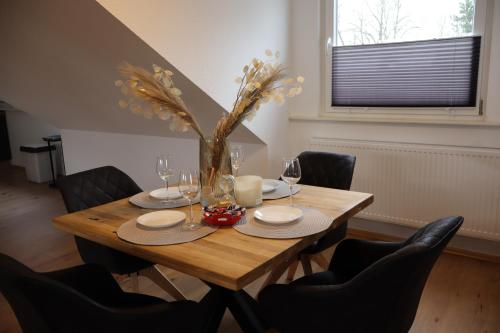 a wooden table with chairs and a vase on it at Hirsch24- 4 Personen Apartment in Lippstadt