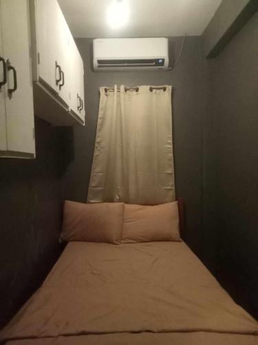 een klein bed in een kleine kamer met een raam bij marivic apartment and staycation in Davao City