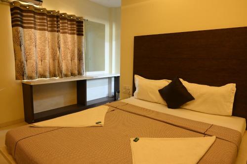 a bedroom with a large bed and a window at Hotel Ramkrishna Inn in Kolhapur