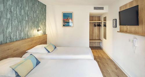 a room with two beds and a flat screen tv at Ostal Pau Universite - Sure Hotel Collection by Best Western in Pau