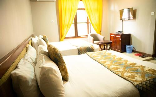 um quarto de hotel com uma cama grande e uma janela em Comfort Inn Mbezi Beach em Dar es Salaam