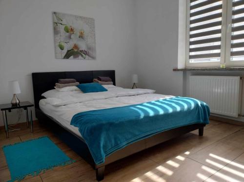 a bedroom with a bed with a blue blanket on it at Apartament Gospodarska in Białystok