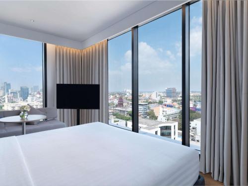 a bedroom with a white bed and a large window at Novotel Phnom Penh BKK 1 in Phnom Penh