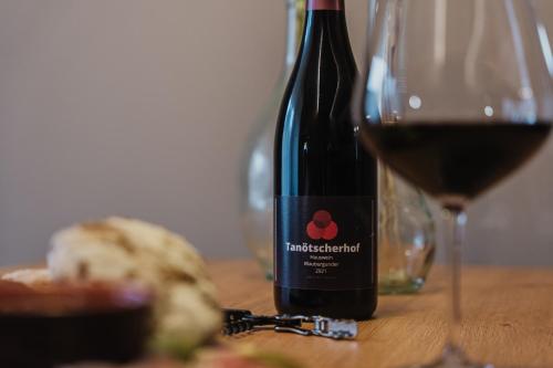 a bottle of red wine next to a glass of wine at TANOVINUM Apartments in Villandro