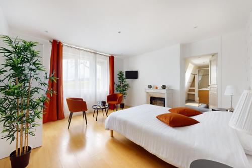 um quarto com uma grande cama branca e uma sala de estar em Chambre dans un manoir au bord de l'Yonne près de Sens em Villeperrot