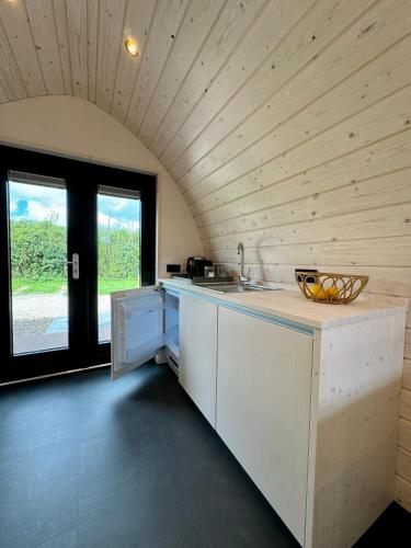 a kitchen with wooden ceilings and a counter with a sink at Camping Zee van Tijd Holwerd in Holwerd