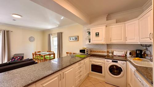 a kitchen with white cabinets and a washer and dryer at Bicos R by Check-in Portugal in Albufeira