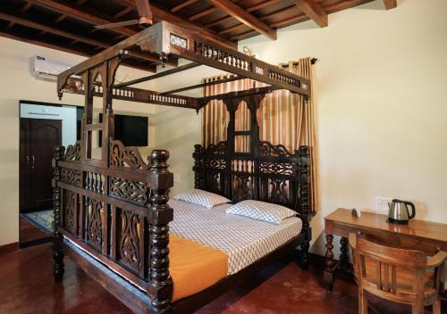 a wooden canopy bed in a room with a desk at Panchavati Villa in Manipala