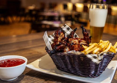a basket of chicken wings and french fries with a glass of beer at Hemingways Hotel in East London