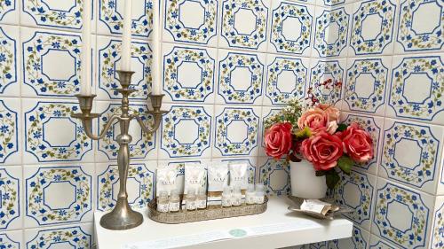 Łazienka z niebiesko-białymi ścianami wyłożonymi kafelkami oraz stołem z kwiatami w obiekcie Bellaria ll w Rapallo