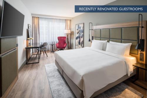 Cette chambre d'hôtel comprend un grand lit et un fauteuil rouge. dans l'établissement Radisson Blu Hotel, Hamburg Airport, à Hambourg
