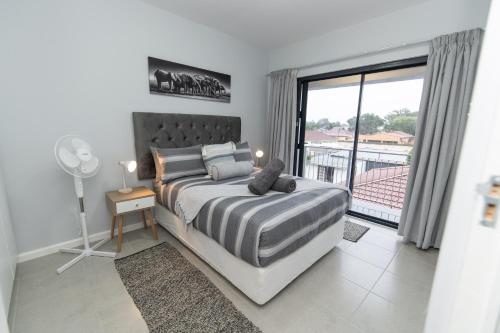 1 dormitorio con 1 cama y vistas a un balcón en The Cozy Traveller, en Gqeberha