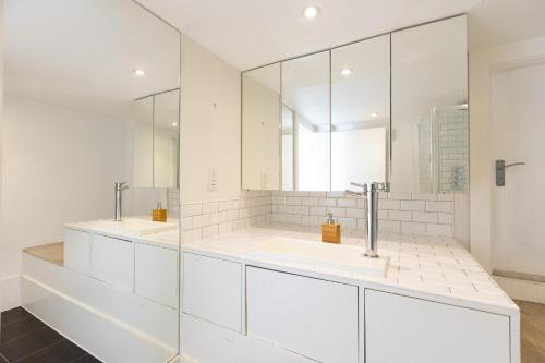 uma casa de banho branca com 2 lavatórios e espelhos em Gorgeous loft style 3BR apt, Battersea em Londres